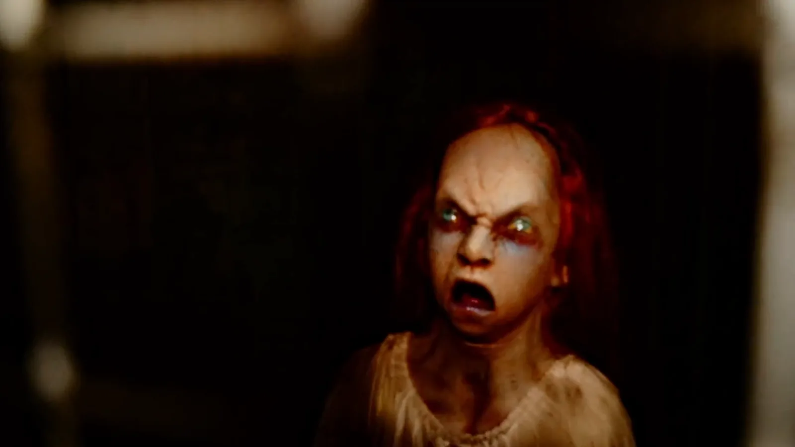 A pale, red-haired ghost girl screaming in the dark of The Possession